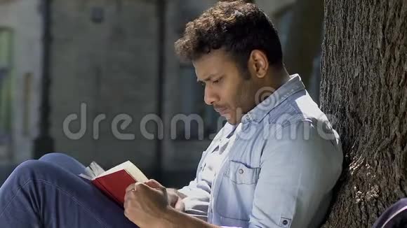 年轻的男性浪漫主义者一头扎进印刷文字阅读书籍的世界视频的预览图