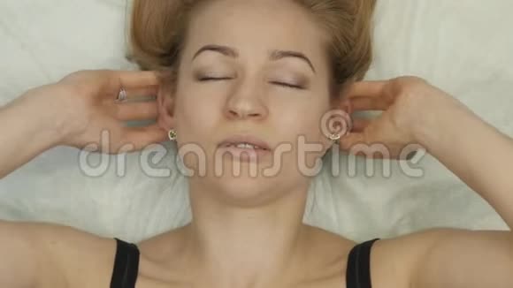 颈部按摩躺在床上金发女性在家做自我按摩抗衰老面部按摩视频的预览图