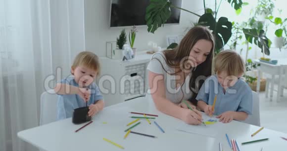 夏天妈妈和她的两个儿子坐在厨房的桌子上画彩色铅笔一家人在草坪上画画视频的预览图