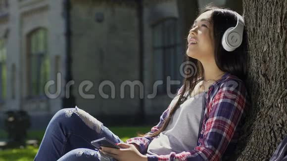 在夏季公园呼吸新鲜空气的混血女孩听着最喜欢的歌视频的预览图