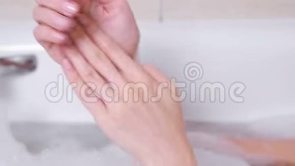 女人剥皮的手把一个擦洗在她的手躺在泡沫浴室双手特写白色背景视频的预览图