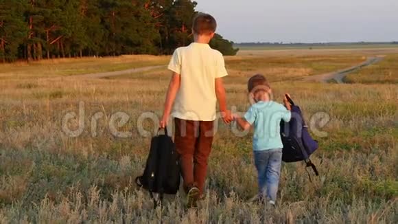 一个游客的两个兄弟背着背包走着在日落时慢动作地牵着手快乐的孩子们走进来视频的预览图
