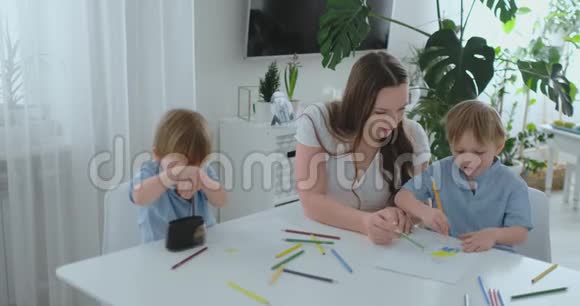 夏天妈妈和她的两个儿子坐在厨房的桌子上画彩色铅笔一家人在草坪上画画男童视频的预览图