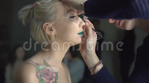 专业化妆流程艺术家正在画室背景下制作一个年轻漂亮模特的脸型视频的预览图