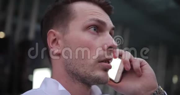 在工作的商人穿着白衬衫的帅哥在电话里说话环顾四周寻找出租车视频的预览图