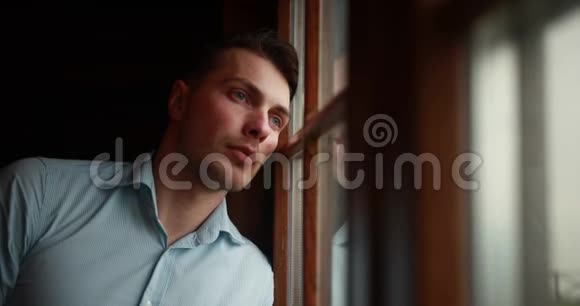 孤独在山里英俊的年轻人倚着窗户闭上眼睛看着傍晚的山视频的预览图
