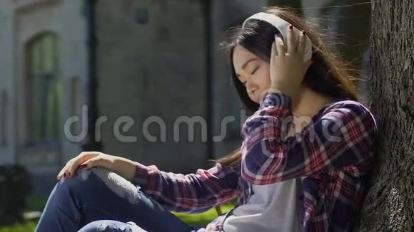 美丽快乐的学生喜欢听她耳机里的音乐视频的预览图