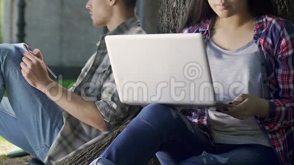几个学生在做作业一个女孩在树下用笔记本电脑视频的预览图