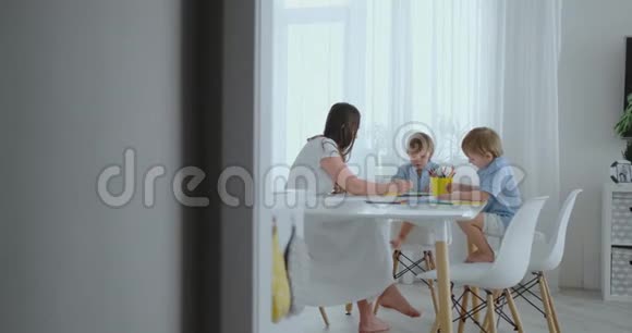 夏天妈妈和她的两个儿子坐在厨房的桌子上画彩色铅笔一家人在草坪上画画视频的预览图