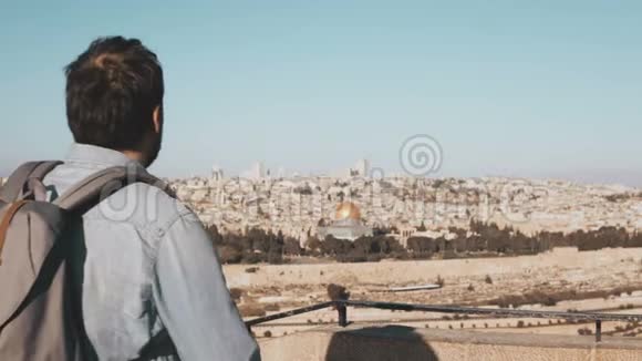 游客男性拍摄耶路撒冷全景照片带背包的人站在智能手机的天空边缘以色列4K视频的预览图