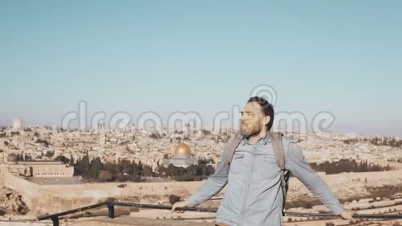 兴奋的欧洲旅游男性环顾四周以色列耶路撒冷快乐的微笑男人与背包享受美丽的景色4K视频的预览图