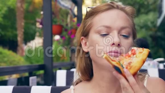 漂亮的年轻女人在咖啡馆里吃披萨特写镜头4k慢镜头视频的预览图
