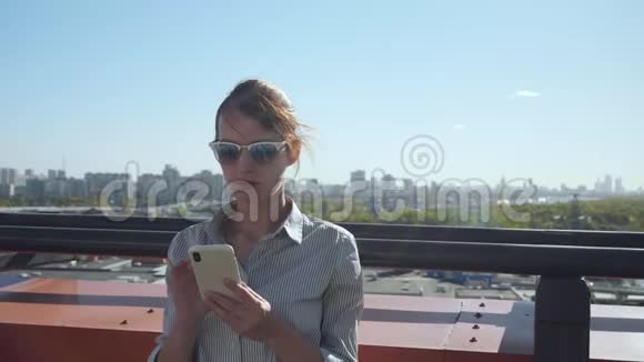 年轻商务女性在阳台上发短信视频的预览图