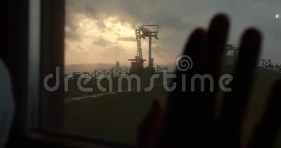男人把手臂放在窗户上窗后是工业山的风景和五彩缤纷的夜空视频的预览图