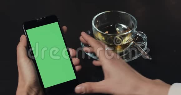 年轻的商务女性使用带有绿色屏幕触摸板的智能手机并在咖啡馆里做手势女孩拿着手机视频的预览图