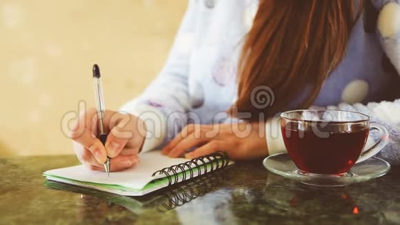 漂亮的年轻女人在日记里写作视频的预览图