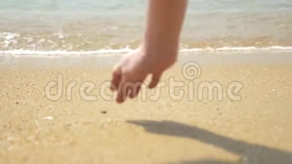 一只雌性的手在潮湿的沙子上画出一颗心4k慢动作视频的预览图