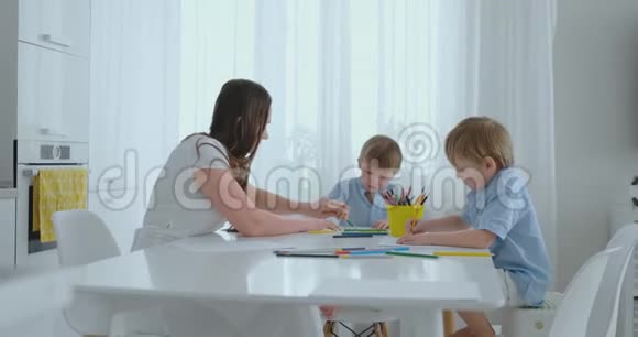 夏天妈妈和她的两个儿子坐在厨房的桌子上画彩色铅笔一家人在草坪上画画男童视频的预览图
