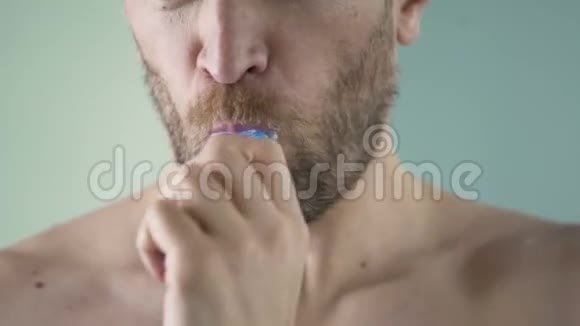 胡须中年男子仔细刷牙照镜子特写镜头视频的预览图