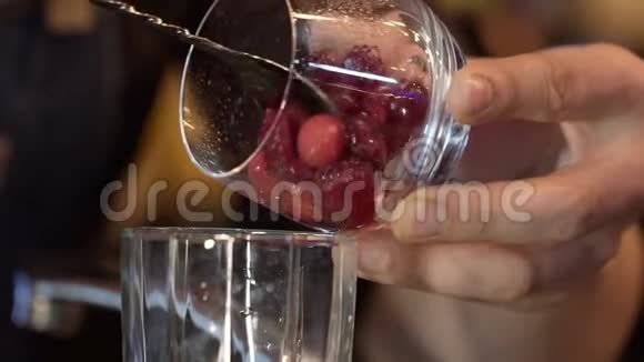 酒保将蔓越莓和覆盆子添加到含酒精的coctail中慢动作视频的预览图