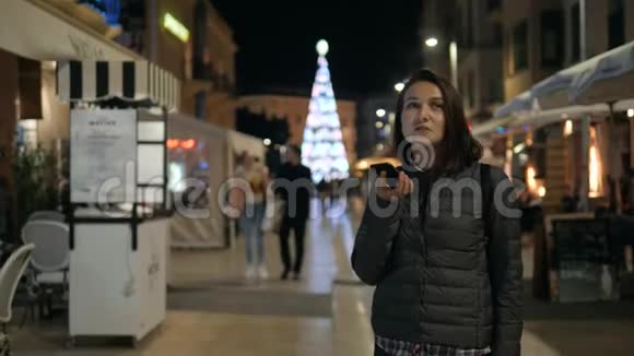 女孩使用智能手机语音识别口述想法语音拨号信息在晚上的街道学生视频的预览图