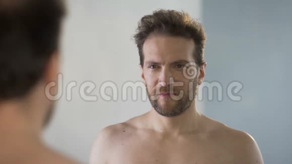 男式自恋者在镜子前调整自己的发型明目张胆地咧嘴笑视频的预览图