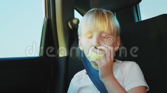 一个6岁的女孩在车里吃苹果在路上容易饥饿和零食视频的预览图