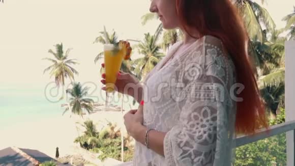 年轻女子在酒店露台上享用新鲜饮料可欣赏海景视频的预览图