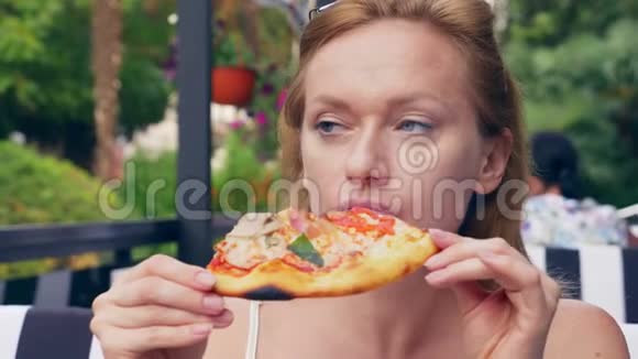 漂亮的年轻女人在咖啡馆里吃披萨特写镜头4k慢镜头视频的预览图