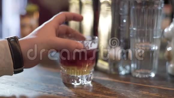 男用手将装有酒精鸡尾酒的玻璃杯放在酒吧柜台上喝含酒精的鸡尾酒视频的预览图