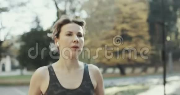 城市公园空中脚蓝牙耳机耳机里有魅力的黑发女子跑步者肖像视频的预览图