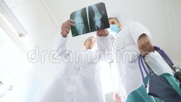 男性医务人员在看x射线图像时互相咨询两名白种人医生观看核磁共振成像并讨论视频的预览图