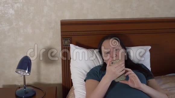 心烦意乱的女人看着智能手机躺在床上视频的预览图