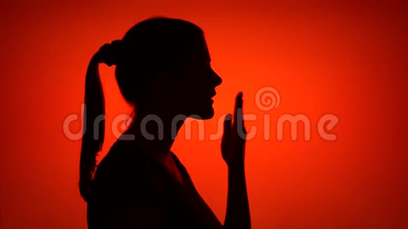 女性在红色背景上做着吹气吻手势的剪影爱情与浪漫的概念视频的预览图