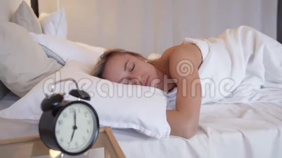 年轻漂亮的女人讨厌一大早醒来熟睡的女孩看着闹钟试图躲在下面视频的预览图