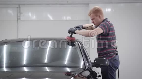 在车库做保护层时师傅正在打磨一个干净的黑色汽车的屋顶视频的预览图