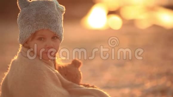 梦中的小女孩抱着一只玩具熊坐在海岸上慢动作看着远处视频的预览图
