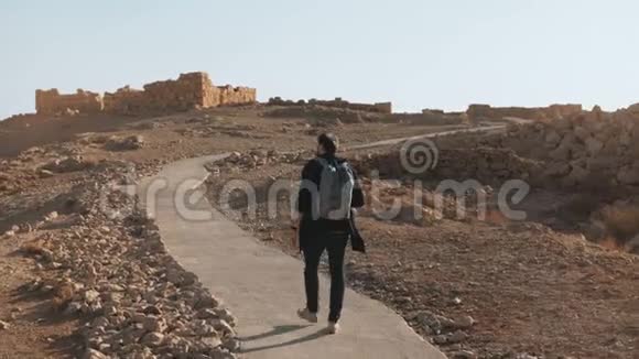 休闲的欧洲游客步行到古老的废墟夏日沙漠之路上放松的男人拍一张智能手机照片以色列4K视频的预览图