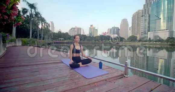 在城市公园的健身地毯上做瑜伽运动后带气足架的年轻女性放松视频的预览图