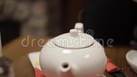 咖啡馆里的女孩用茶打开茶壶的盖子看是否冲泡然后关上视频的预览图