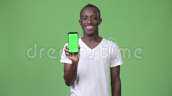 年轻快乐的非洲男人一边笑着一边看手机视频的预览图