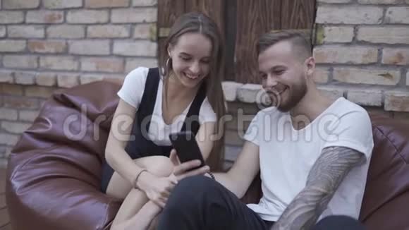 现代时尚情侣在智能手机上看着有趣的东西笑着视频的预览图