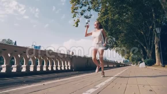 美丽的女孩享受大自然沿着水边的街道奔跑和跳跃很漂亮的年轻女人视频的预览图