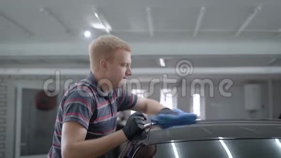 汽车维修师傅在一个工作间用抹布擦拭车顶抛光视频的预览图