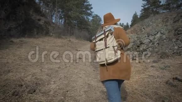 积极健康的时髦少年在森林徒步旅行年轻的女旅行者穿过森林一顶帽子和一个旅行者视频的预览图
