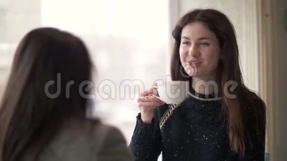 女青年在咖啡厅与朋友见面时喝咖啡聊天视频的预览图