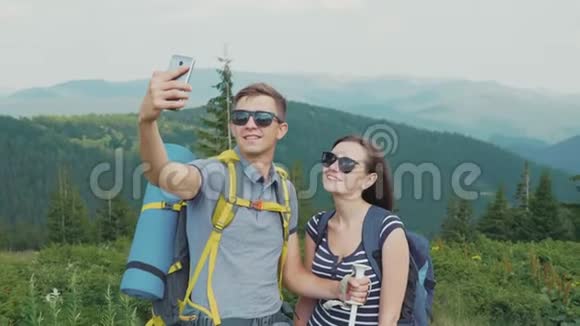 快乐的蜜月一对年轻夫妇在山上拍照一起徒步旅行视频的预览图