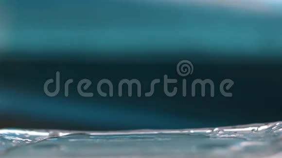 在1080p的蓝色背景下1000fps慢动作下落在玻璃瓶上的水滴宏观视频的预览图