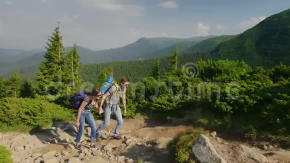 一个男人在爬山时帮助他的女朋友积极的生活方式视频的预览图