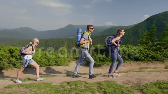 一群游客在山上徒步旅行他们走在风景如画的群山背景下晴朗的夏日视频的预览图